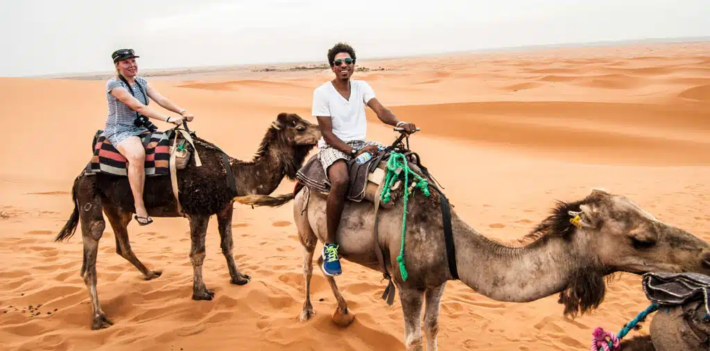 Man and Woman on Camels in sand dunes of Morocco