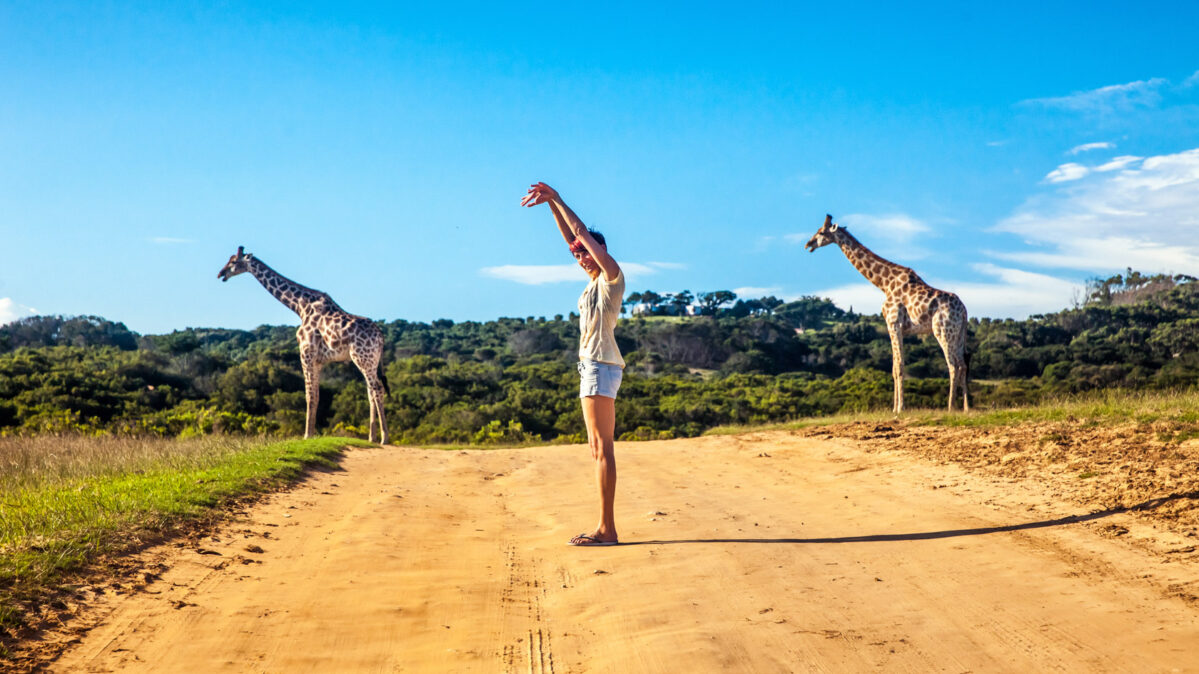 Girl standing next to a Griaffe.