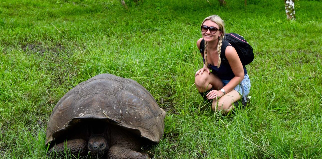A woman leaning down to look at a turtle.
