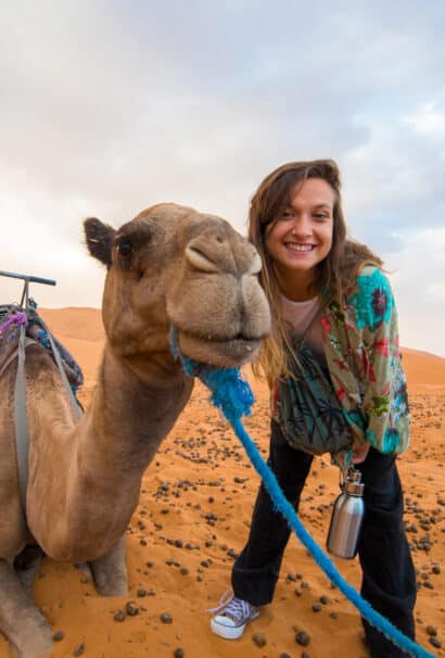 A girl posing next to a camel.