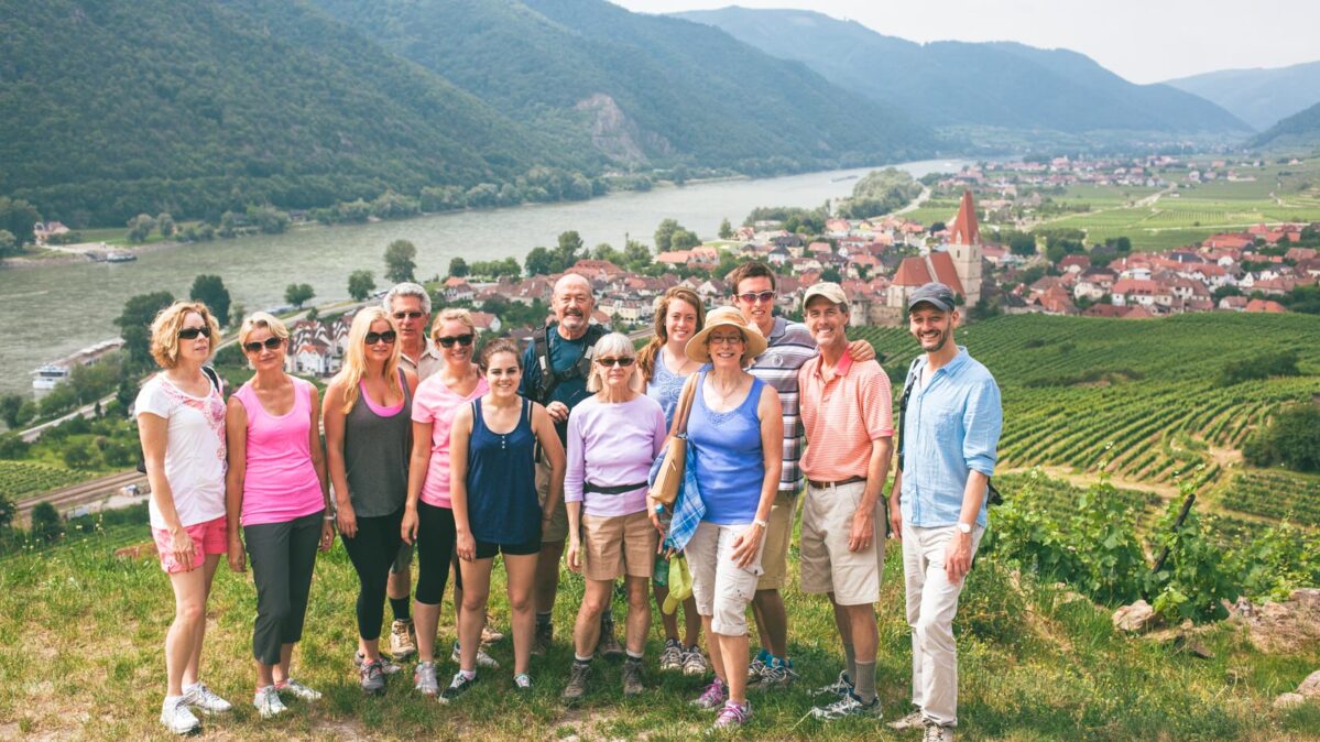 group of people in Austria by river and vineyards.