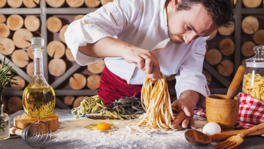 A man sprinkling pasta.