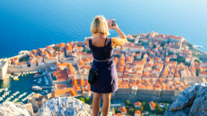 A girl taking a picture of a city landscape in Croatia.