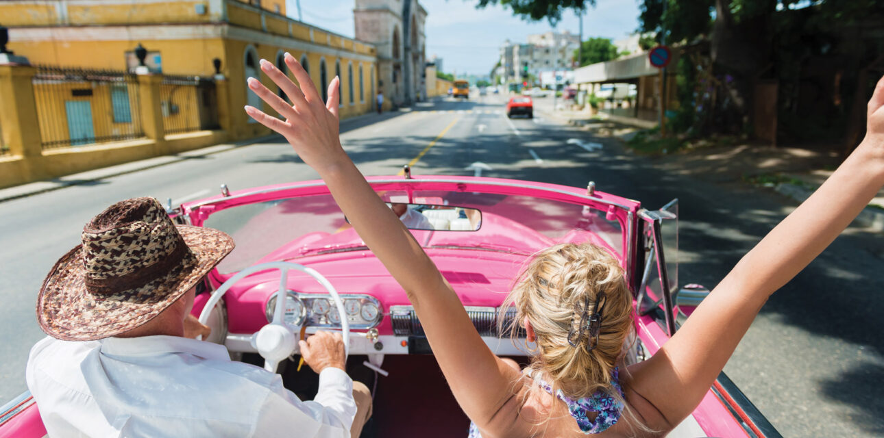 People driving in a convertible in Cuba.