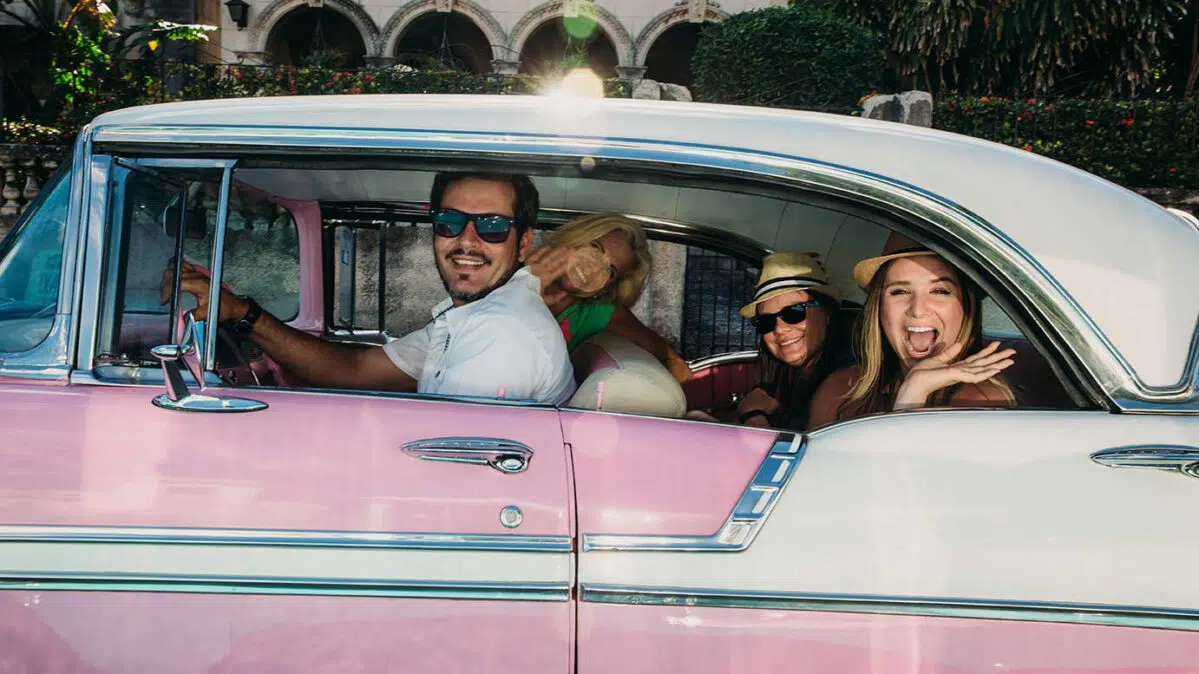 People driving in a convertible in Cuba.