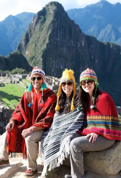 Three young people sitting by Machu Picchu.
