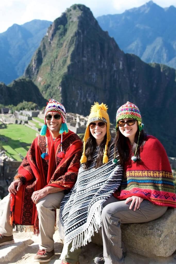 Three young travelers sitting by Machu Picchu in Peru