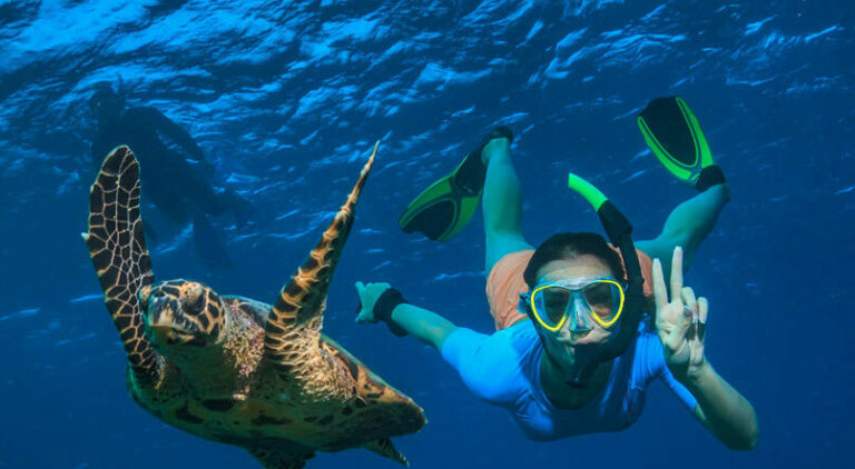 A boy snorkeling in the Galapagos with a sea turtle