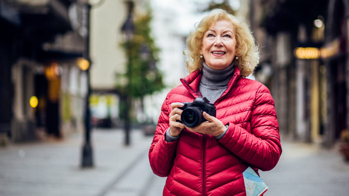 An elder woman taking a picture of where she's traveling.