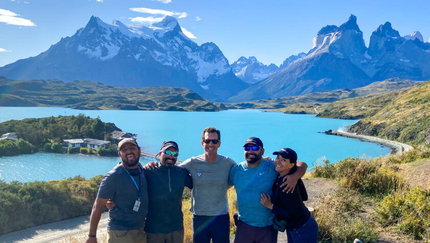 A group shot of tour guides with a mountain landscape backdrop.