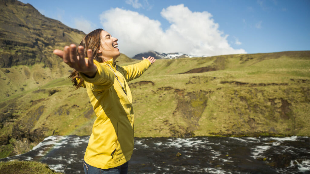 A woman smiling with her arms outstretched in Iceland