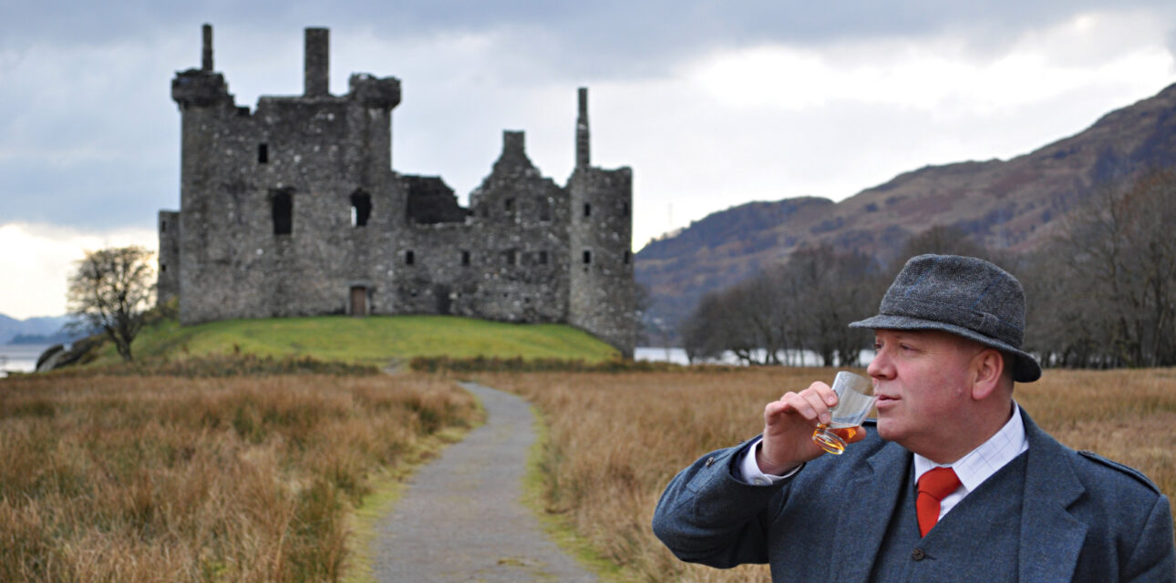 A man drinking next to a castle in the UK.