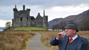 A man drinking next to a castle in the UK.