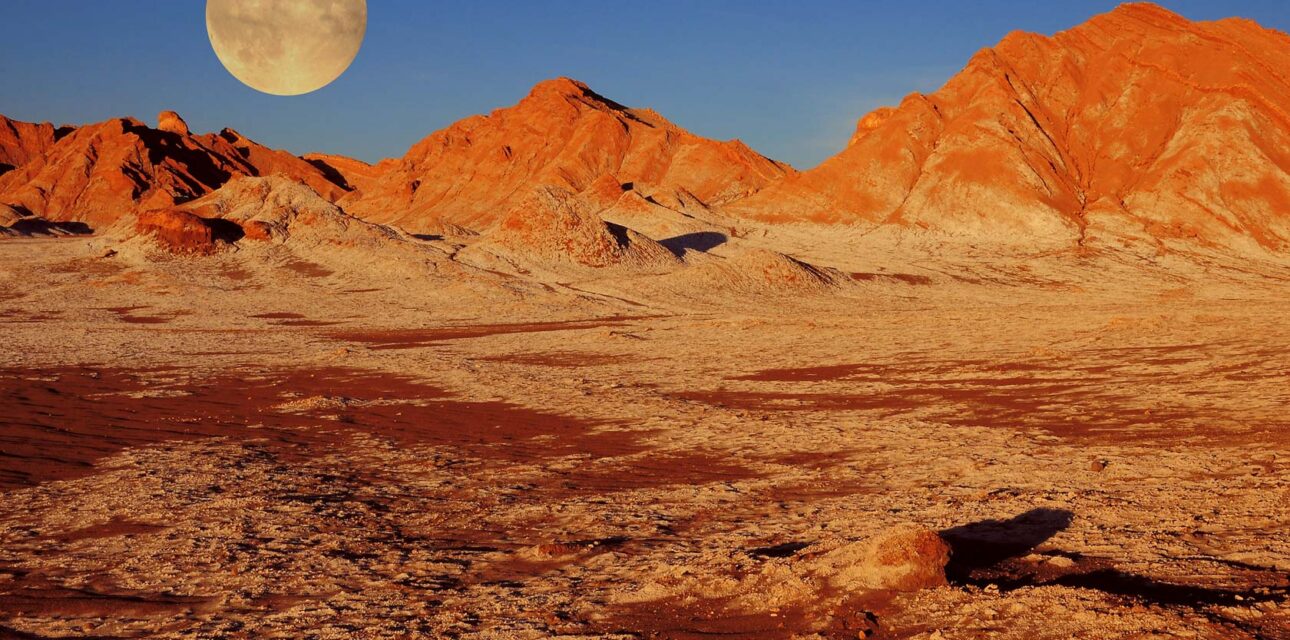 A sunset view of the moon and mountains in Chile.