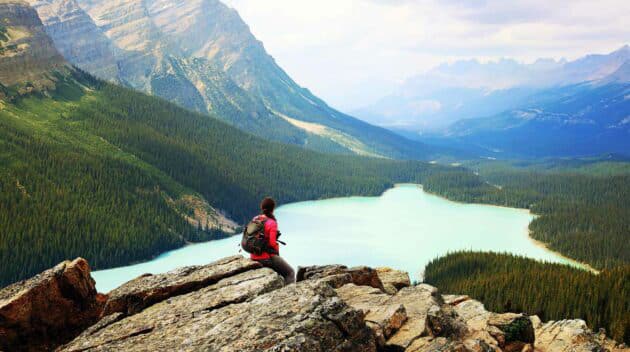 man sitting on a cliff looking out into the distance.