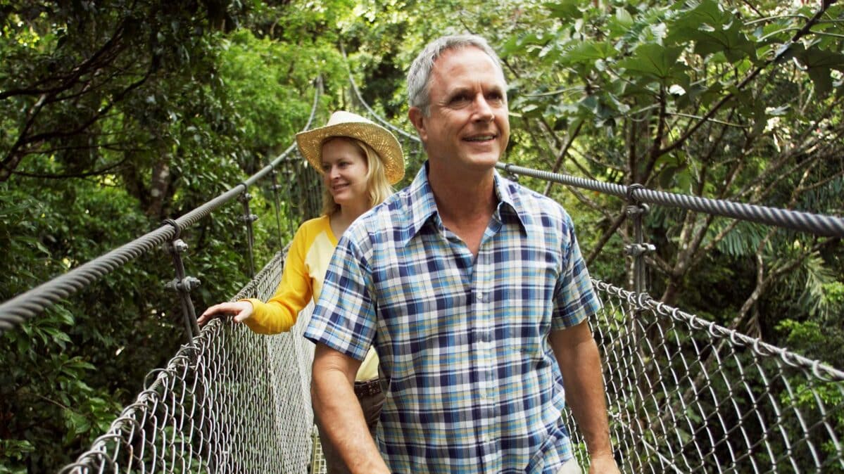 Man and woman walking on a rope bridge.