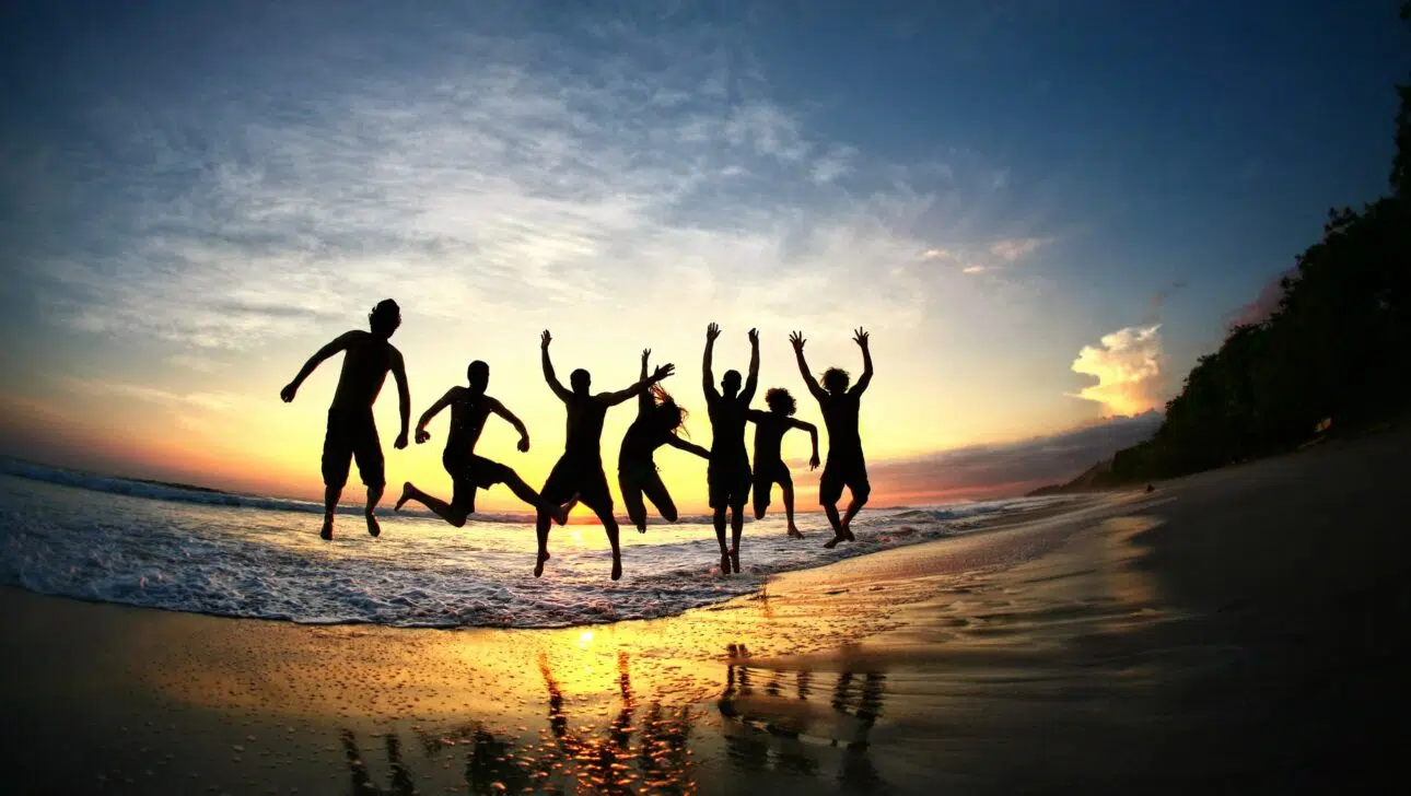 Family jumping together on a beach during sunset