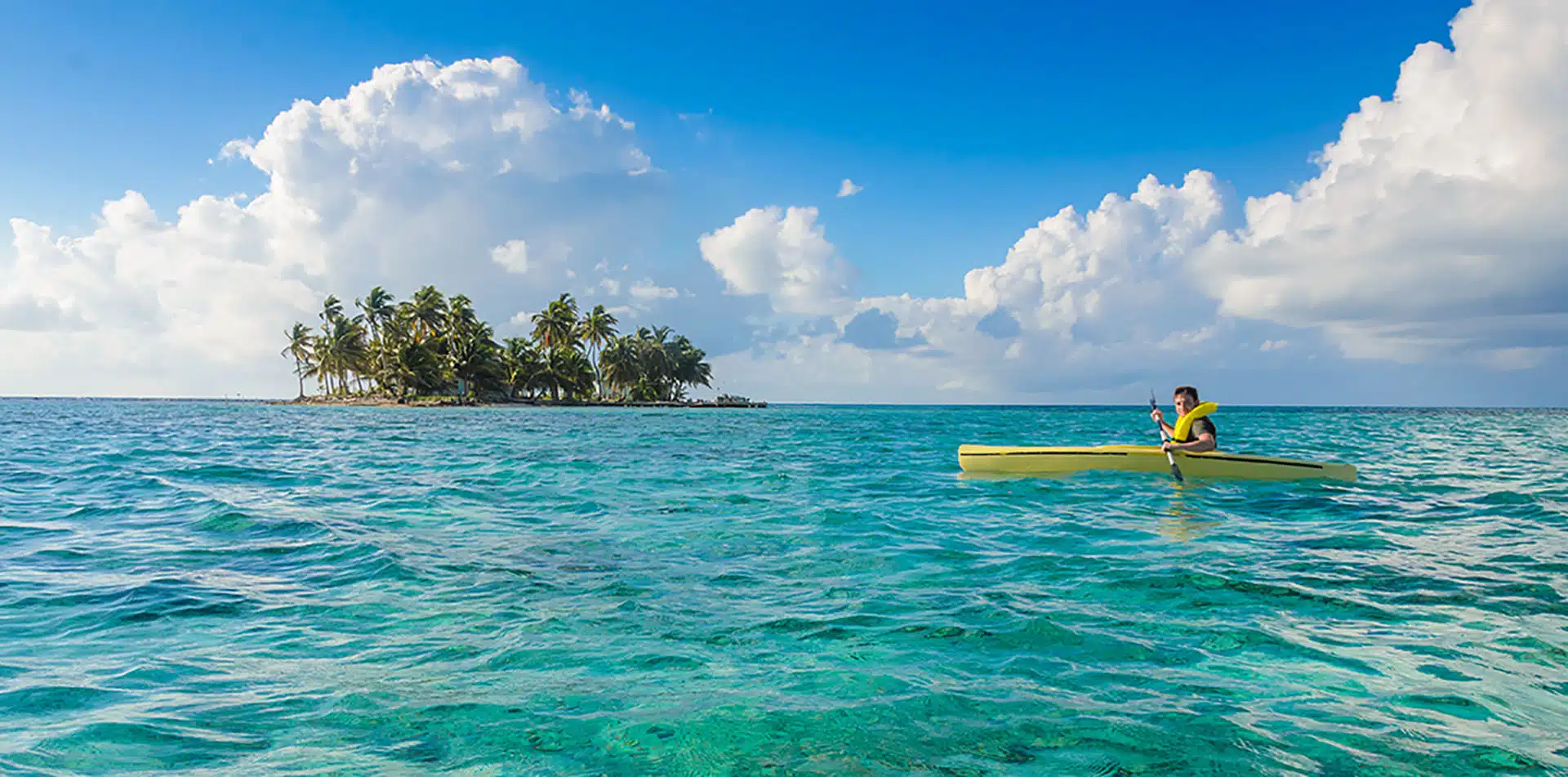 Central America Belize Cayes Islands tropical clear turquoise water man smiling yellow kayak - luxury vacation destinations