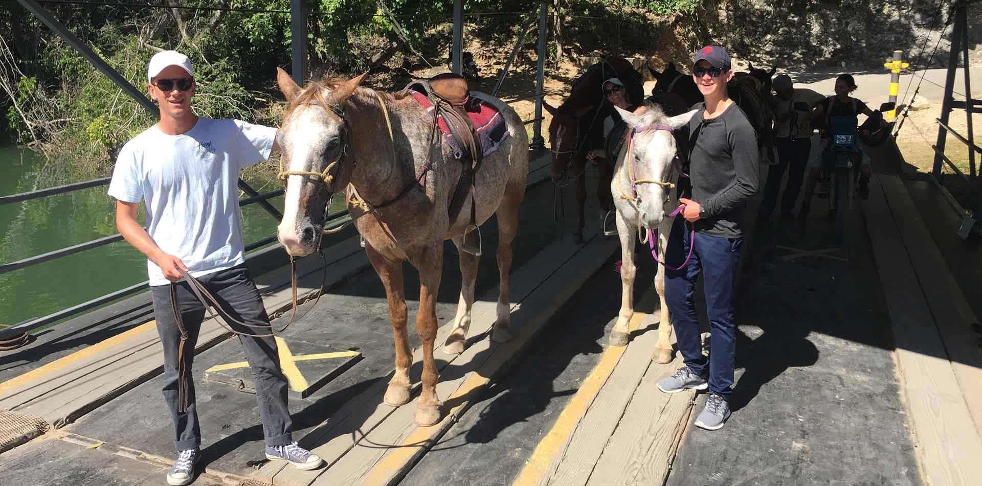 Central America Belize group standing next to horses on bridge smiling - luxury vacation destinations