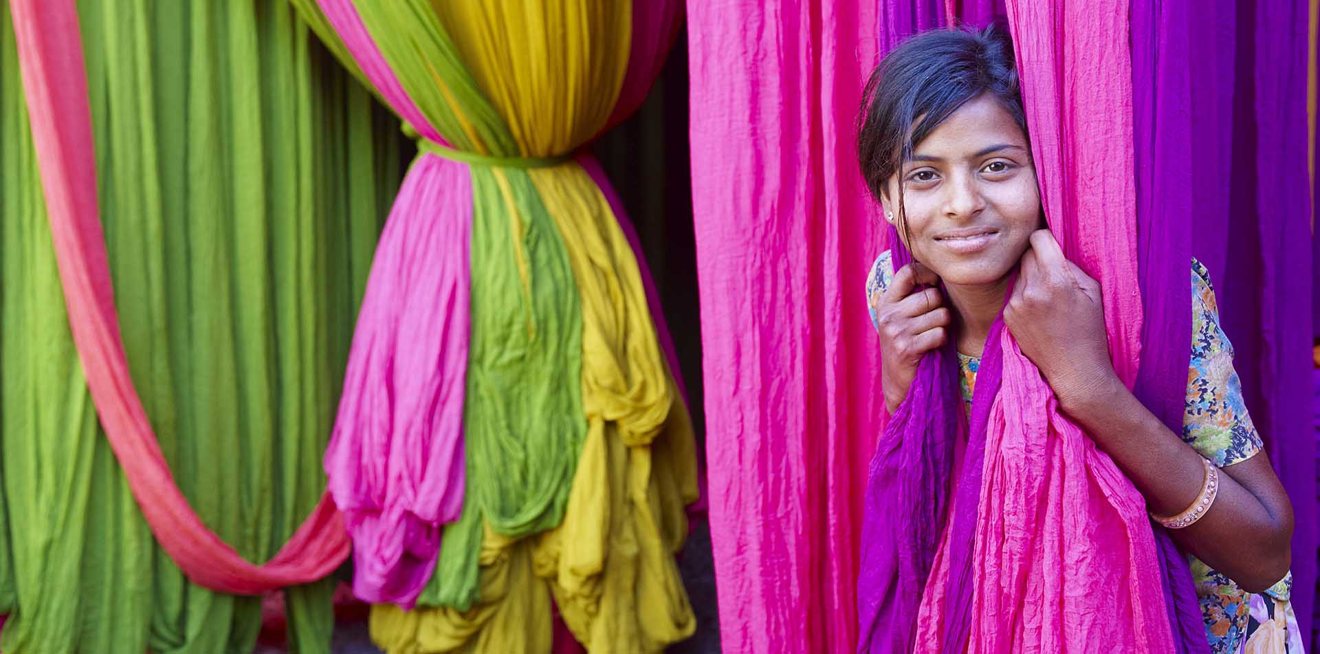 Girl Standing Among Colorful Textiles, India