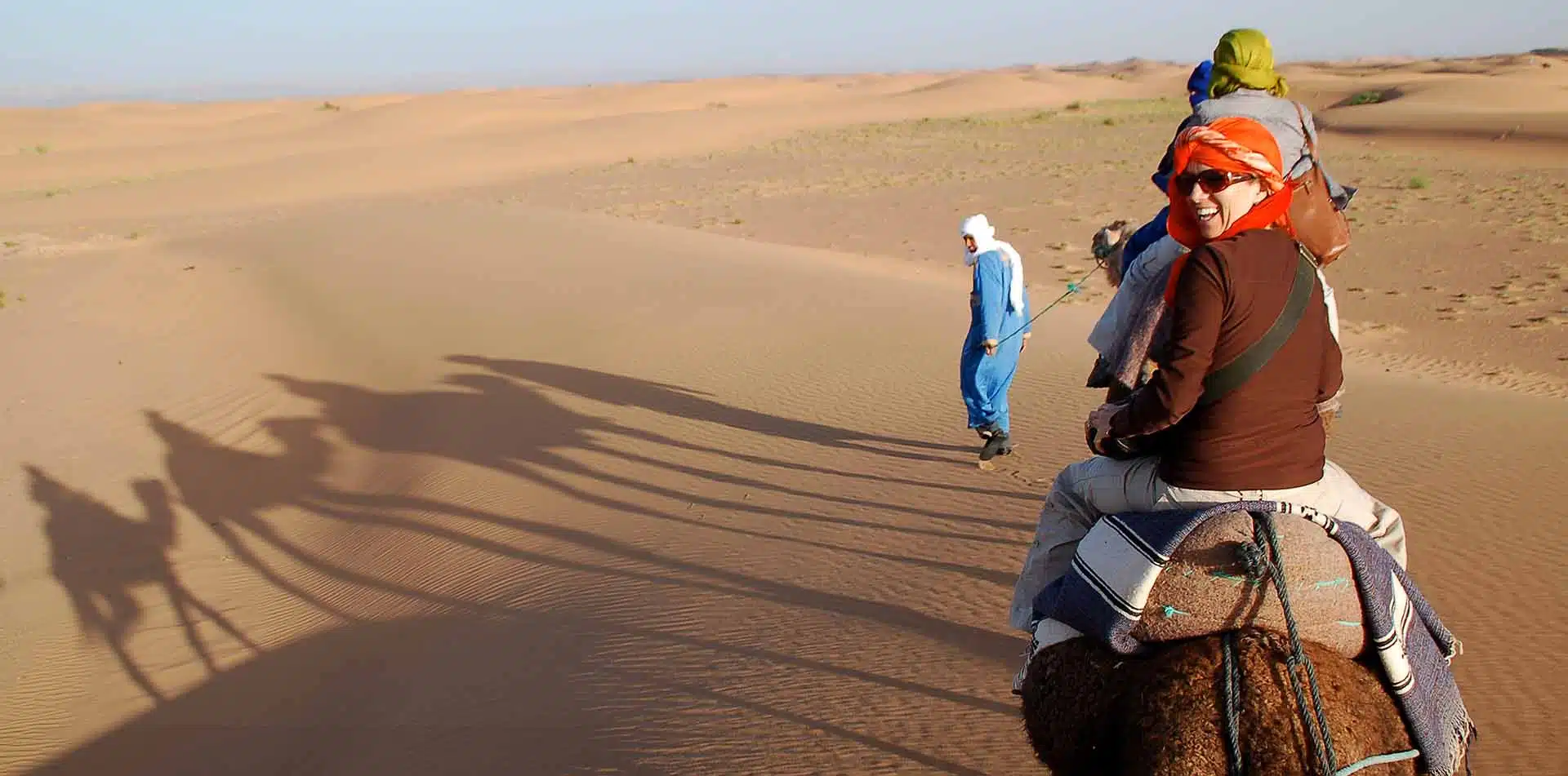 Classic Journeys Founder Susan Piegza on a camel in sand dunes of Morocco