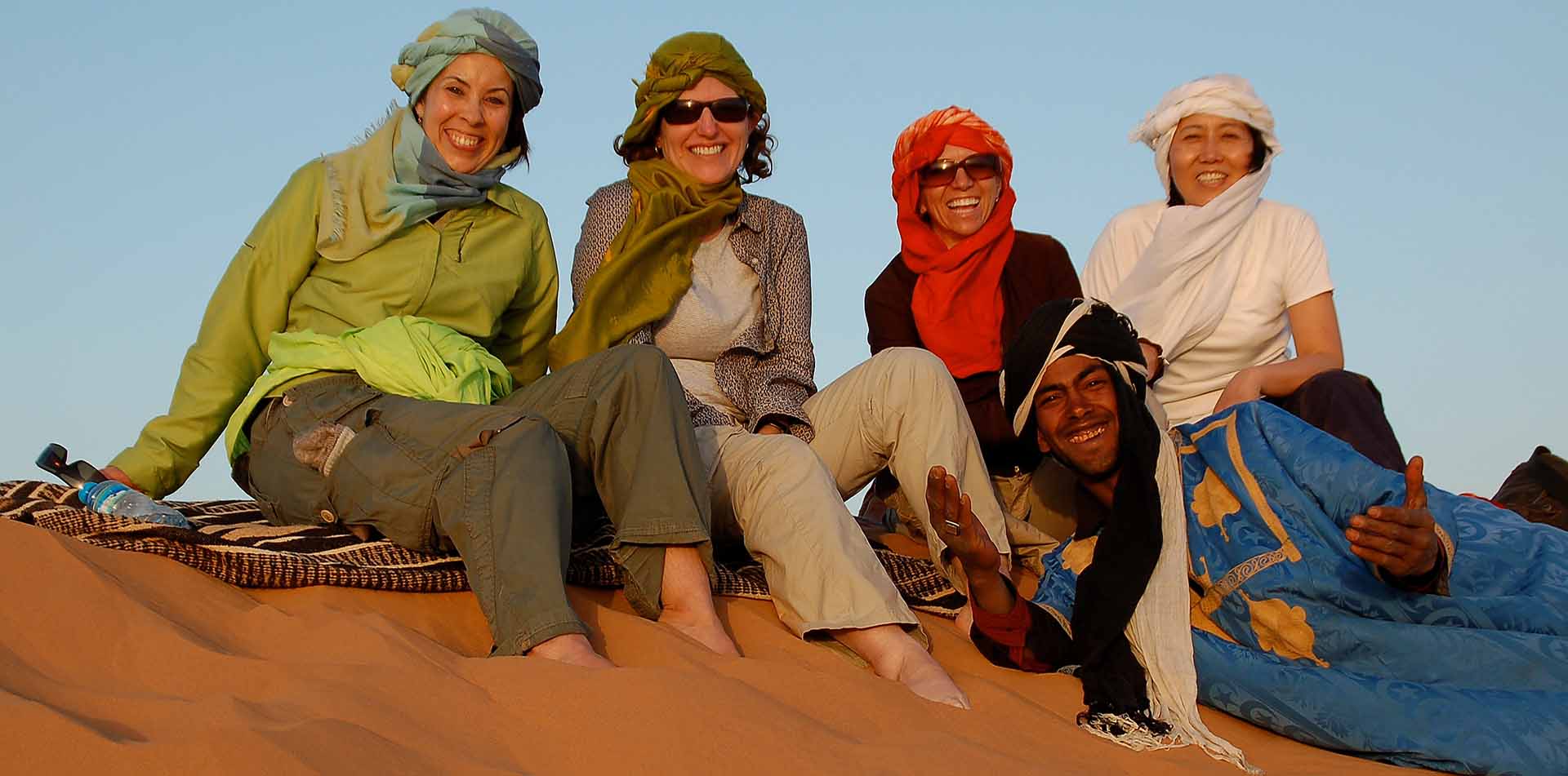 Classic Journeys Guide Saida with Travelers on Sand Dune in Morocco
