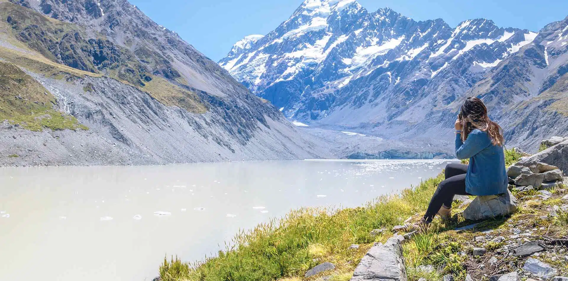Traveler sitting on the edge of Hooker Glacier in New Zealand