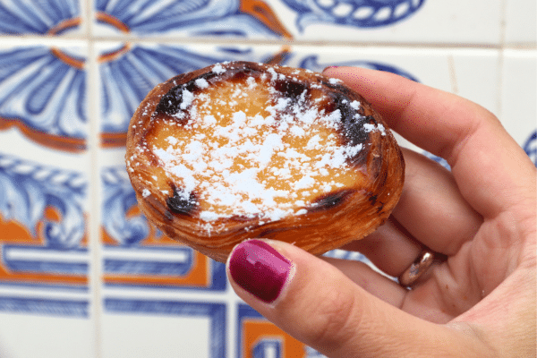 Pastel de Nata pastry in a Lisbon bakery with blue tile in the background