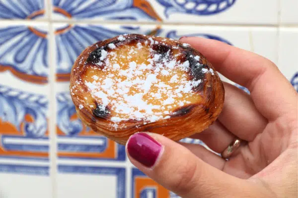 Pastel de Nata pastry in a Lisbon bakery with blue tile in the background