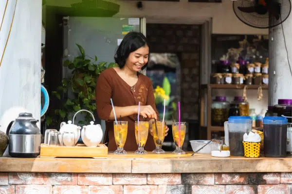 Young smiling woman preparing drinks in street cafe in Saigon, Vietnam