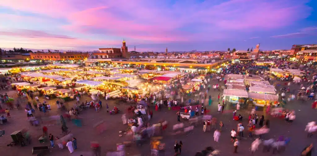 Lively Moroccan market with brightly lit tends and large crowd of people coming and going