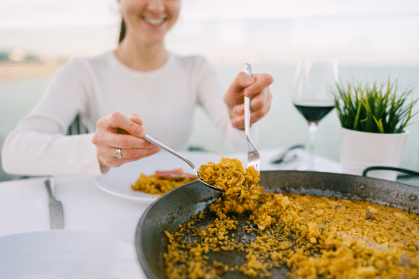 Happy tourist woman eating Paella seaside