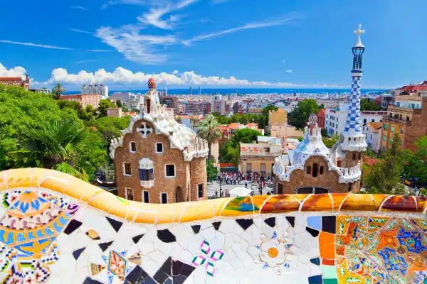 Walk through the colorful Park Guell in Barcelona with the city skyline below the park