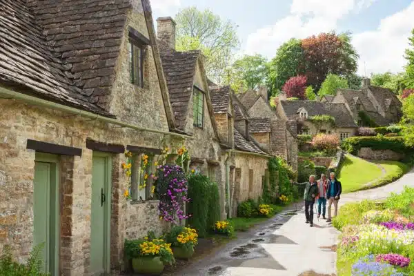 Travelers strolling in Cotswolds next to brick cottages