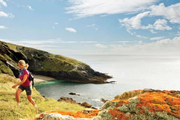 Woman walking by the ocean shore in Cornwall