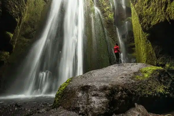 Icelandic waterfall with traveler looking up at the natural wonder