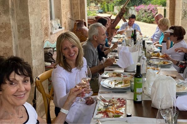 Group eating and drinking at a table for lunch in Puglia, Italy