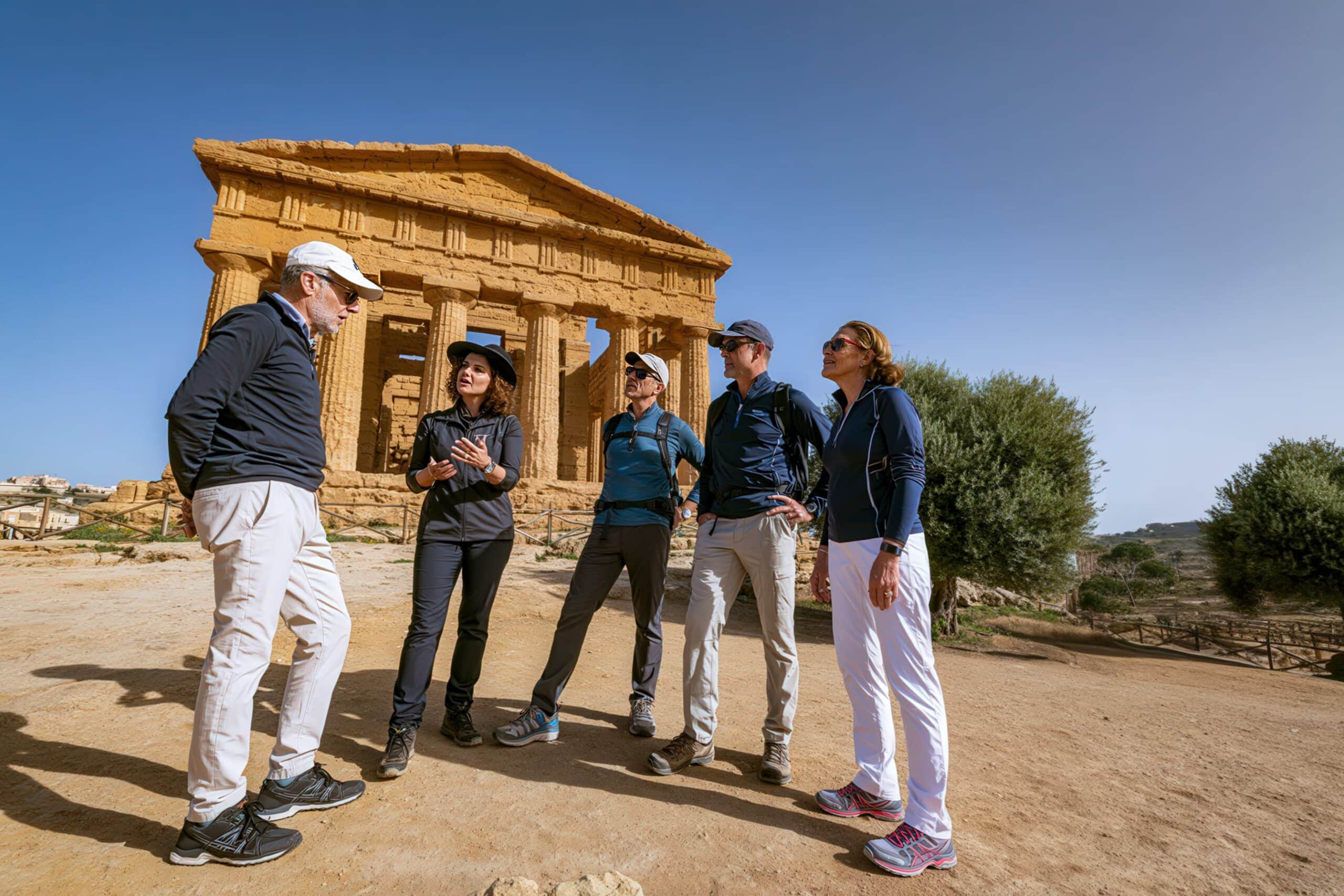 Classic Journeys guests listening to a local guide beside an ancient Greek temple at the Valley of the Temples in Agrigento, Sicily.