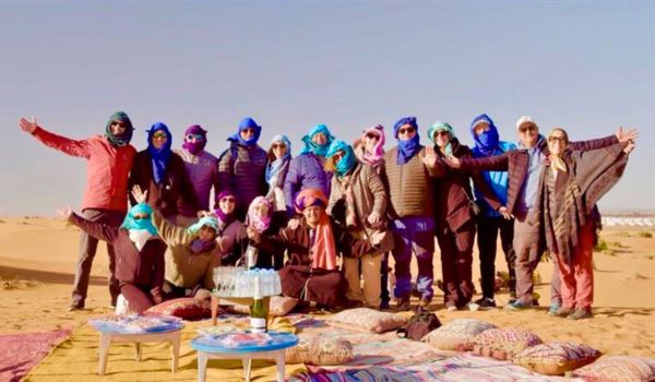 Group of travelers in Moroccan desert having fun on tour