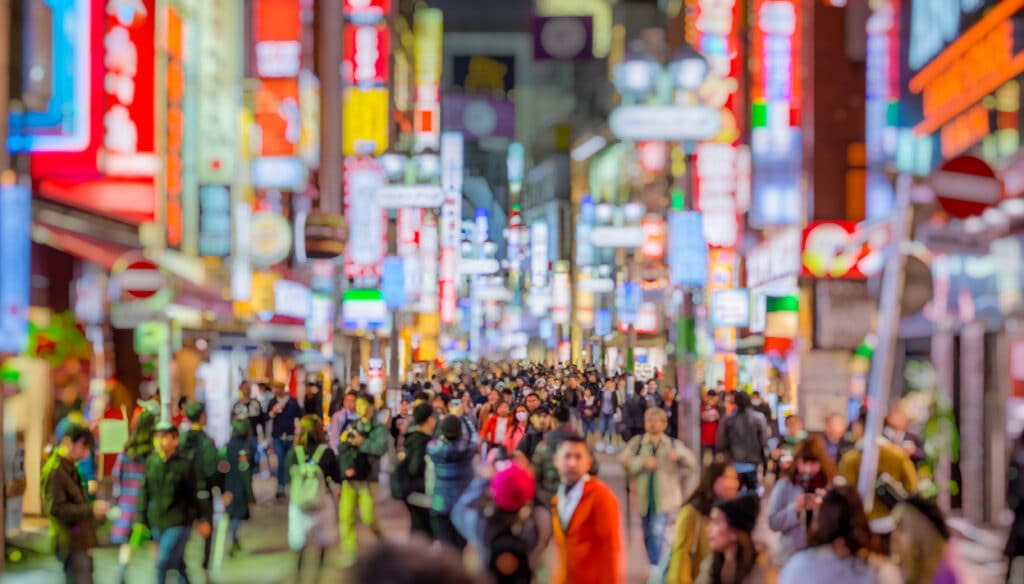 Crowded city street in Japan illuminated by colorful signs at night