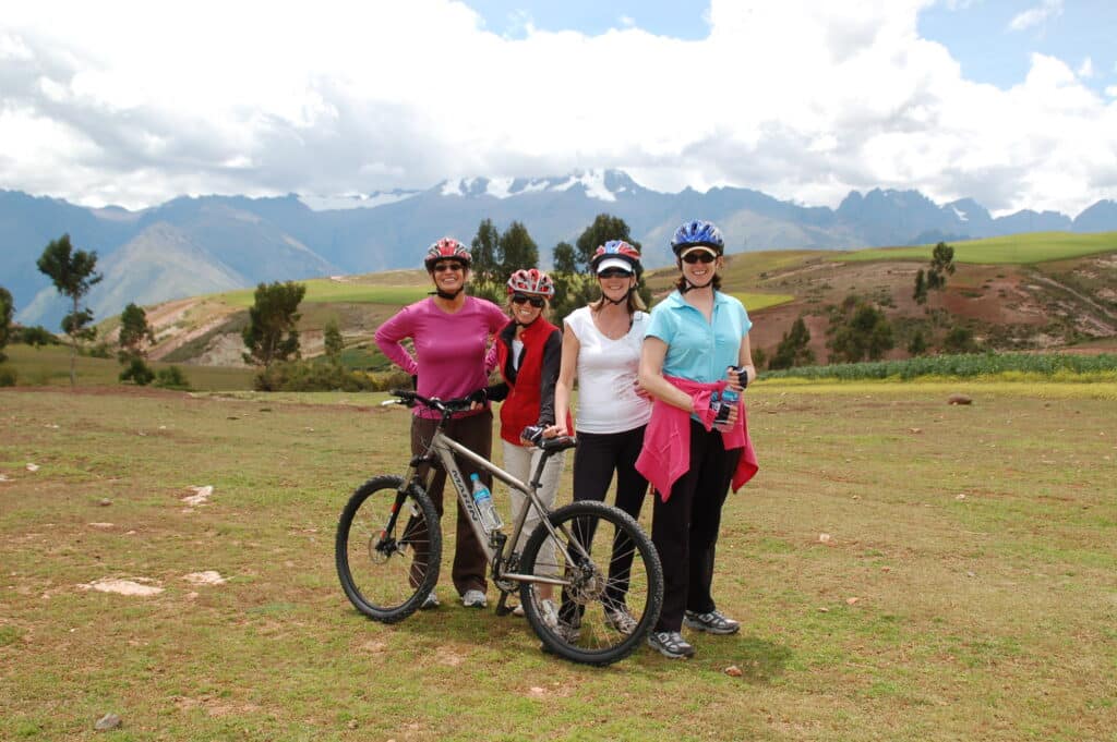 Four women with bicycles in Peru’s Sacred Valley, surrounded by mountains.
