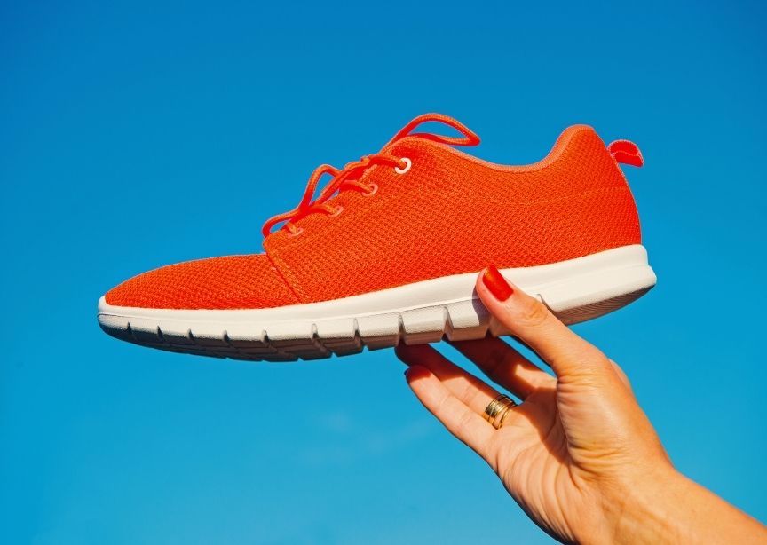 Female hand red nails holding red sneaker throwing shoes for Czech holiday tradition