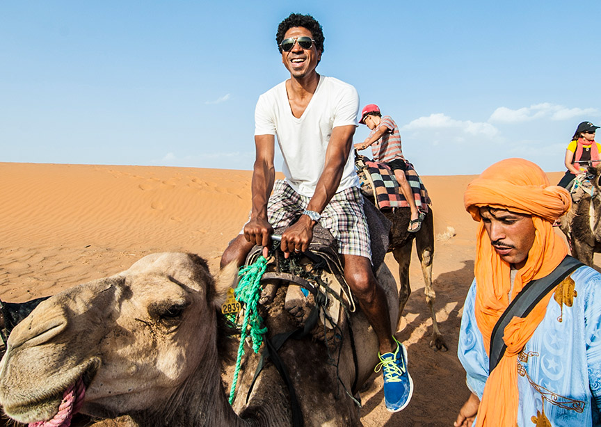 Happy traveler riding camel in Morocco