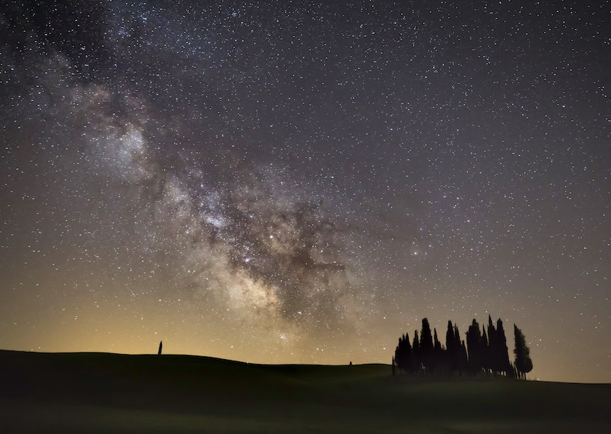 Italy Tuscany Field at Night with Trees silhouetted and starry skies milky way